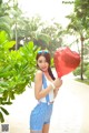 A woman holding a red heart shaped balloon in her hand.