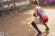 A woman in a red and white uniform holding a basketball on a court.