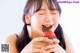 A young girl eating a chocolate covered strawberry.