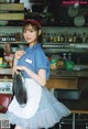 A woman in a blue shirt and white apron holding a tray.