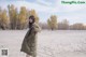 A woman standing in the middle of a sandy field.